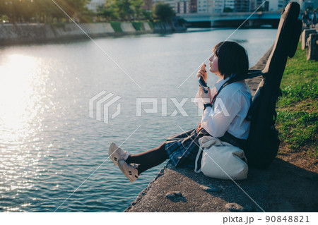 ギターとスマートフォン持った制服姿の女子高生と街 ギターとスマートフォン持った制服姿の女子高生と街 90848821