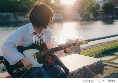 ギターを弾いている制服姿の女子高生と街 90849094