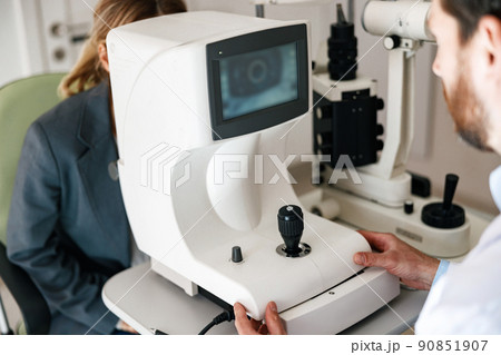 Close up of male oculist checking vision for patient with ophthalmic equipment 90851907