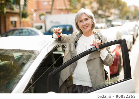Mature lady standing beside car 90852265