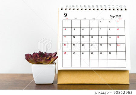 September 2022 desk calendar with plant on wooden table. 90852962