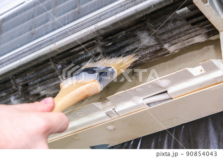 man cleans an air conditioner with a brush. Split man cleans an air conditioner with a brush. Split 90854043