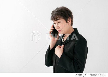 喪服の女性　スマートフォン　葬儀 90855429