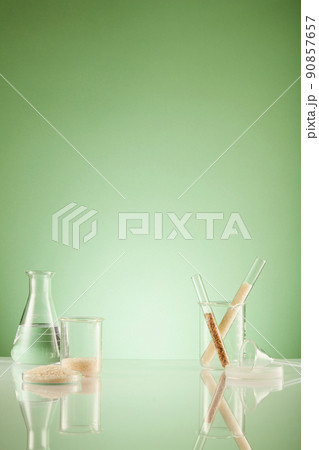 Front view of scientist working with chemical reaction in chemistry laboratory rice in transparent test tube and green blackground with blank space for advertising Front view of scientist working with chemical reaction in chemistry laboratory rice in transparent test tube and green blackground with blank space for advertising 90857657