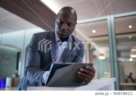 Portrai of African American businessman using  laptop of mobile device  in modern office. 90858622