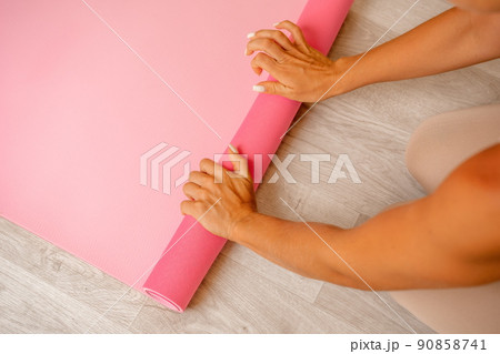 Well looking middle aged woman with long hair, fitness instructor in beige sportswear, doing stretching and pilates on yoga mat in the gym. Healthy lifestyle, harmony. Female fitness yoga meditation. 90858741