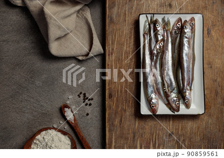 Small raw fish on a wooden board. Top view, low key Small raw fish on a wooden board. Top view, low key 90859561