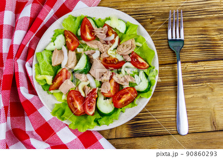 Tasty tuna salad with lettuce and fresh vegetables on wooden table. Top view Tasty tuna salad with lettuce and fresh vegetables on wooden table. Top view 90860293