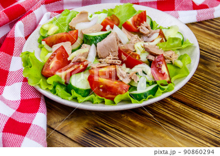 Tasty tuna salad with lettuce and fresh vegetables on wooden table 90860294