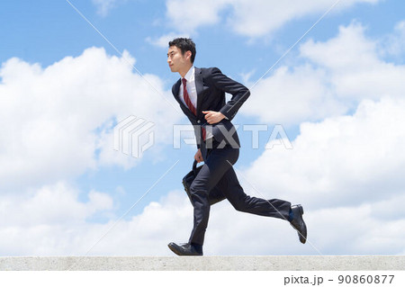 青空のもとで前傾姿勢で走るビジネスパーソン 90860877