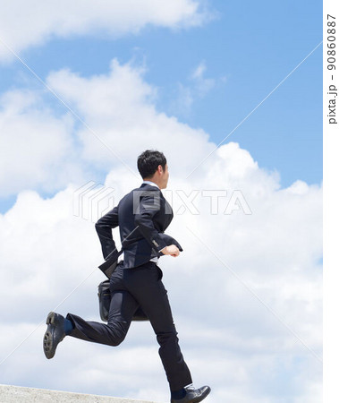 青空を駆け抜けるスーツ姿のビジネスパーソン 青空を駆け抜けるスーツ姿のビジネスパーソン 90860887