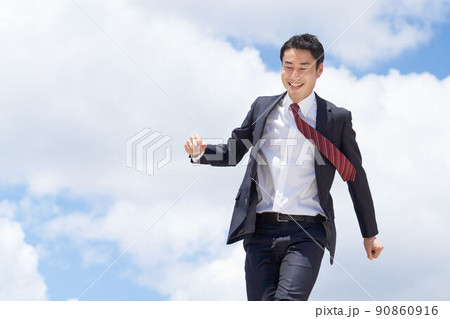 青空のもと歩きながら笑顔を見せるビジネスパーソン 90860916