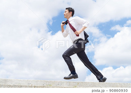 青空のもとジャケットを肩にかけて走るビジネスパーソン 90860930