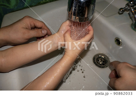 Close up of caucasian man and child washes his hands in the bathroom. COVID - 19 prevention Close up of caucasian man and child washes his hands in the bathroom. COVID - 19 prevention 90862033