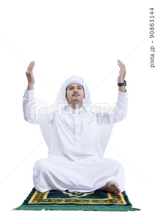Muslim man praying while sitting on the prayer rug Muslim man praying while sitting on the prayer rug 90863144