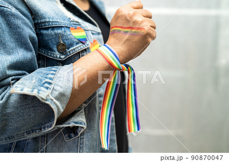 Asian lady wearing rainbow flag wristbands, symbol of LGBT pride month celebrate annual in June social of gay, lesbian, bisexual, transgender, human rights. Asian lady wearing rainbow flag wristbands, symbol of LGBT pride month celebrate annual in June social of gay, lesbian, bisexual, transgender, human rights. 90870047