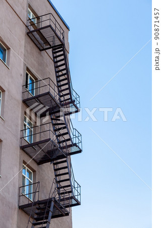 Silhouette of a fire escape on a high-rise building against a blue sky Silhouette of a fire escape on a high-rise building against a blue sky 90871457