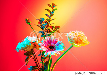 Beautiful bouquet of flowers, abstract floral composition in glass vase over pink, magenta background in neon light. Concept of floristry, decorations, creativity, decor 90873379