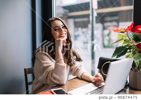 Positive woman using laptop for working in cafe at daytime 90874475