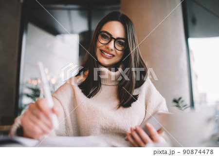 Positive woman writing in planner and browsing smartphone Positive woman writing in planner and browsing smartphone 90874478