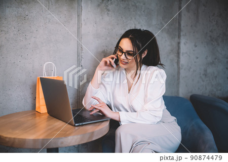 Cheerful female manager talking on smartphone at cafe 90874479