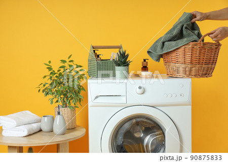 Concept of housework with washing machine on yellow background 90875833