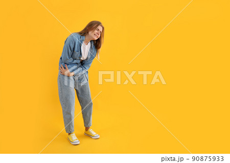 Girl with abdominal pain on yellow background Girl with abdominal pain on yellow background 90875933