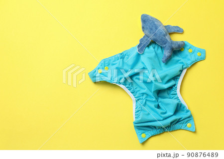 Concept of baby clothes with reusable diapers on yellow background Concept of baby clothes with reusable diapers on yellow background 90876489