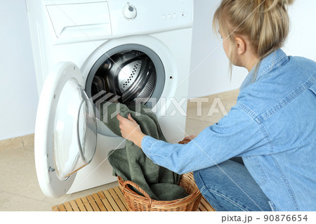 Concept of housework with washing machine and girl against white wall Concept of housework with washing machine and girl against white wall 90876654