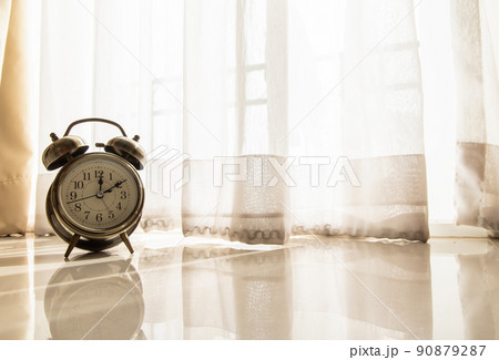 Alarm clock in the room that have early light through the beautiful curtain for background. Alarm clock in the room that have early light through the beautiful curtain for background. 90879287