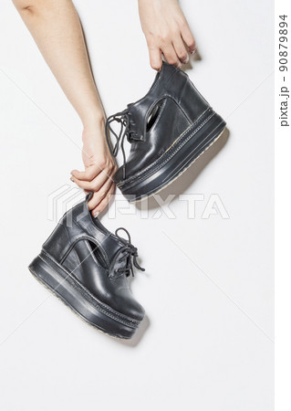 Woman holding stylish boots on white background Woman holding stylish boots on white background 90879894
