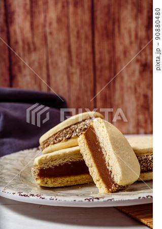 Argentine classic alfajores of cornstarch and dulce de leche with coconut on a vintage plate. Vertical Orientation. Copy text. sweet snack Argentine classic alfajores of cornstarch and dulce de leche with coconut on a vintage plate. Vertical Orientation. Copy text. sweet snack 90880480