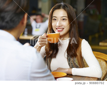 young asian couple lovers sitting at table chatting talking face to face in coffee shop 90880702