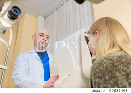 A male ophthalmologist checks the eyesight of a young girl using a modern vision tester A male ophthalmologist checks the eyesight of a young girl using a modern vision tester 90881463
