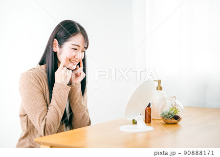 部屋で鏡を見る肌荒れが治った女性（スキンケア・笑顔） 90888171