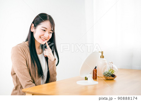 部屋で鏡を見る肌荒れが治った女性（笑顔・口） 90888174