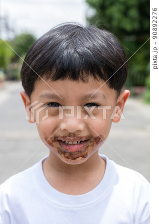 Child face messy and dirty by chocolate ice cream. 90892276