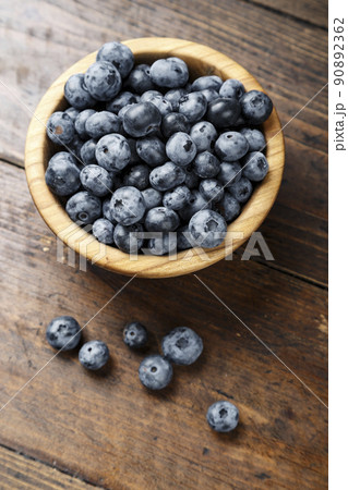 Freshly picked blueberries in wooden bowl on wooden background.   90892362