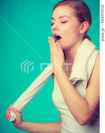 Bored sleepy woman yawning while holding towel Bored sleepy woman yawning while holding towel 90895010