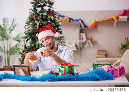 Young man celebrating Christmas at home alone Young man celebrating Christmas at home alone 90895468