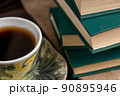 A cup of strong tea on a saucer and a stack of books on the table 90895946