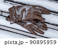 Brown leather gloves forgotten on a snow-covered bench in a winter park 90895959