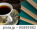A cup of strong tea on a saucer and a stack of books on the table 90895982