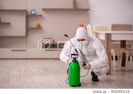 Young male contractor doing pest control at home 90896816