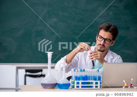 Young male chemist in front of blackboard Young male chemist in front of blackboard 90896992