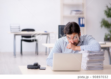 Young male employee and too much work in the office Young male employee and too much work in the office 90897032