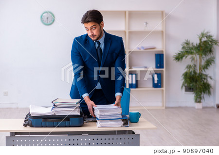 Young male employee preparing for business trip at workplace Young male employee preparing for business trip at workplace 90897040