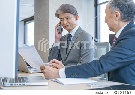 書類を見ながらスマホで会話するシニア男性2人 書類を見ながらスマホで会話するシニア男性2人 90901163
