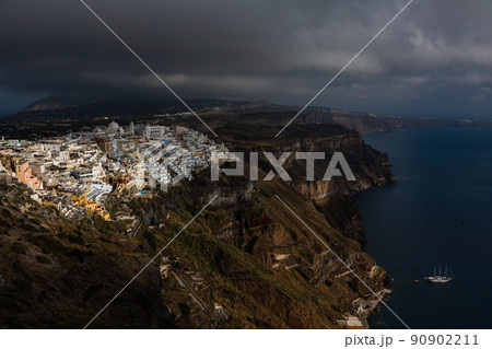 ギリシャ　サントリーニ島の断崖の上にある陽が差し込んで照らされたフィラの街並みとエーゲ海 90902211