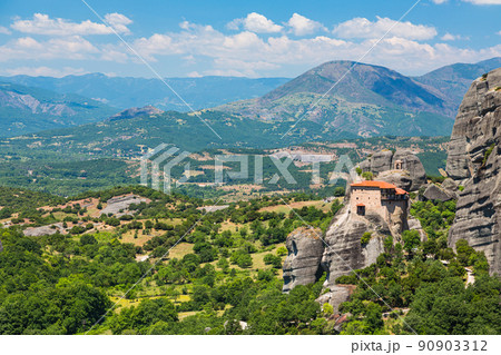ギリシャ　メテオラの断崖絶壁の岩山の上に建つ聖ニコラオス・アナパフサス修道院と後ろに広がる山 90903312